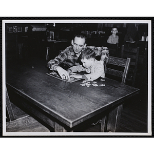 A man assists a boy with assembling a puzzle