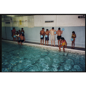 Children with balloons gather at the edge of a natorium pool