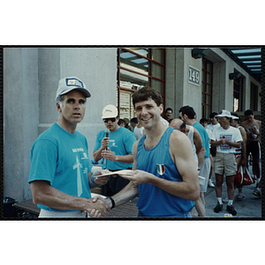 A man hands another a certificate man as they shake hands at the Battle of Bunker Hill Road Race