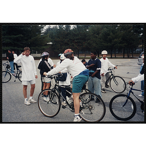 Teenagers gather with their bicycles in a parking lot as Executive Director Jerry Steimel looks on