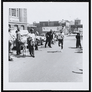 A teenage boy completes the Roxbury Road Race as spectators look on