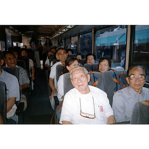 Chinese Progressive Association member smiles, sitting on a bus filled with fellow members