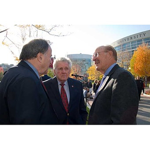 Three men converse outdoors at the Veterans Memorial dedication ceremony