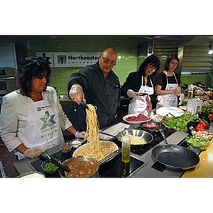 Four people cook when the Torch Scholars visit the Exhibition Kitchen