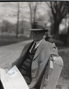 Clarence E. Jacobson: seated on a bench with a copy of the Boston Herald