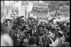 Gary Hart walking through a crowd of press and supporters after renewing his bid for the Democratic nomination for the presidency