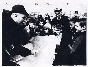 Mayor John F. Collins pointing at map as unidentified man and a group of children observe