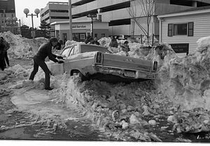 Unidentified man opening door of car buried in snow on Cambridge Street