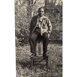 Man perches on the back of a chair