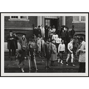 Runners descend the steps of a building as spectators look on during the Roxbury Road Race