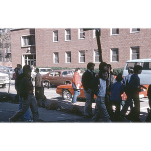 Adults and teenagers stand on a city block in Boston's Chinatown