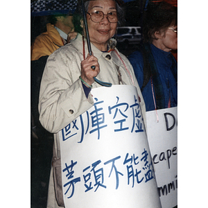 Woman wears a sign during a protest in the rain