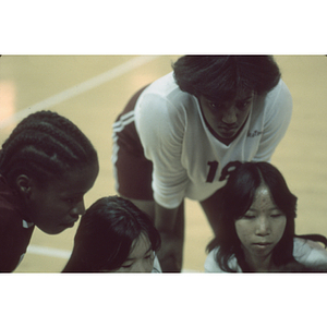 Female volleyball players huddle during a break from play