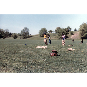 Association members compete in a sack race, while a boy behind them throws a football to other children