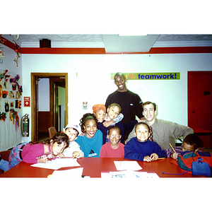 Unidentified elementary students and young adults pose in a classroom