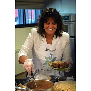 A woman serves up a plate of food when the Torch Scholars visit the Exhibition Kitchen