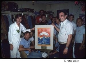 MUSE concert and rally: Graham Nash (left), Jackson Browne (fourth from right) and concert staff holding framed concert poster backstage at the MUSE concert