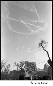 View of a skywriting peace symbol dissolving above a sing reading 'Bring the boys home -- Gay Liberation Front'