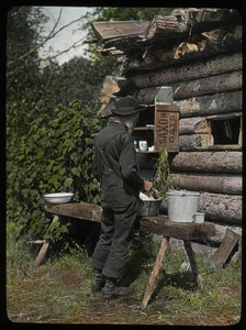 Washing dishes in camp P.Q.(elderly man outside log camp)