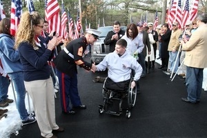 Kevin Dubois and his wife Kayla come up the flag-lined driveway, MSgt. Jonathan Braca, Wounded Warrior Regiment R.I., reaches out to shake his hand