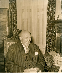 W. E. B. Du Bois seated in carved wood victorian armchair, smiling