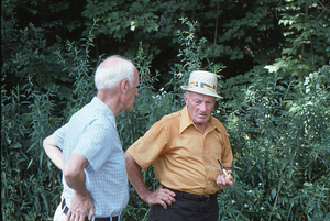 Unidentified man chats with Harvey Cummings (in hat) of Petersburg Road at Moon Barn Raising at entrance to Hopkins Forest on 2 August 1975.