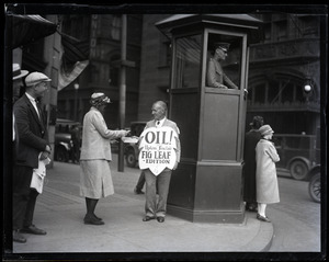 Upton Sinclair selling a copy of his novel Oil! during censorship hearings, standing next to a police box and wearing a sandwich board reading 'Oil!... fig leaf edition'