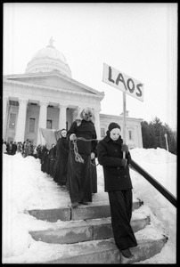 Bread and Puppet Theater descending the steps at the Vermont State House, dressed in cloaks and masks and carrying a sign reading 'Laos' during a demonstration against the invasion of Laos