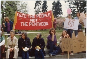 Antinuclear protesters seated beneath a banner reading 'Feed the people, not the Pentagon'