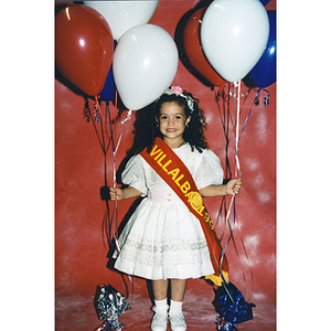 A young girl dons a Villalba 1996 sash and holds balloons at the Puerto Rican Festival