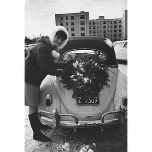 A girl places a wreath on the back of a car in the snow