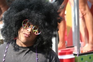 Man in a huge black wig and multicolored peace symbol glasses : Provincetown Carnival parade