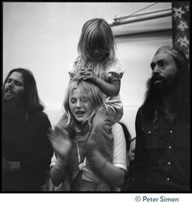 Child hoisted on the shoulders of a woman watching Ram Dass at Sonoma State University