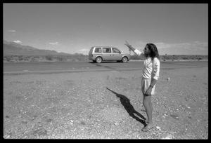 Peace encampment activist waving at a passing vehicle on the road near the entrance to the Nevada Test Site