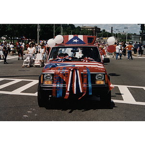A truck covered in Puerto Rican flags and red, white, and blue ribbons in the parade for the Festival Puertorriqueño