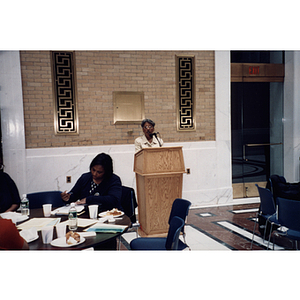 Carmen Pola speaks from the lectern at a town hall meeting