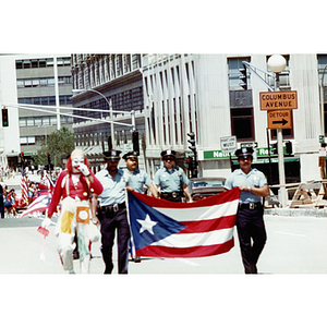 Police officers carry a Puerto Rican flag down Columbus Avenue in Roxbury during the Festival Puertorriqueño parade