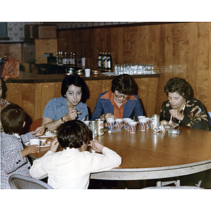 Three women and two children eat at a round table