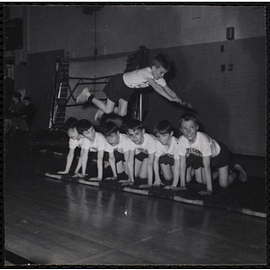 A boy jumps over six boys on their hands and knees in the South Boston gymnasium on Physical Fitness Day