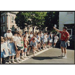 Children and teenagers take instruction from a man at the start line of the Battle of Bunker Hill Road Race