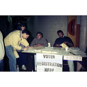 Men reviewing papers at a voter registration table