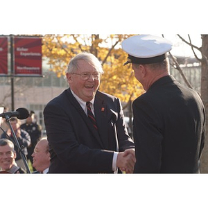 Neal Finnegan shakes a uniformed man's hand at the Veterans Memorial dedication ceremony