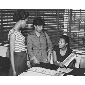 Three students look at co-op handbooks during a minority open house at the African-American Institute