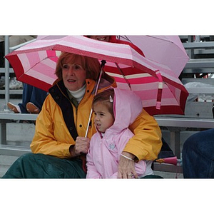 Two fans huddle under an umbrella during the Homecoming game