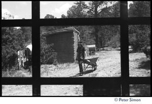 View through a window of man and wheelbarrow, Lama Foundation