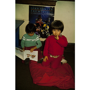 Boys seated on the floor and reading a storybook