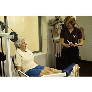 Woman talks to a trainer while exercising in a gym