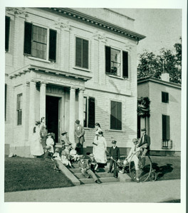 Stereo view of Lyman family on front steps of the Lyman Estate, Waltham, Mass, before 1886 renovation. Includes young man seated on a bicycle.