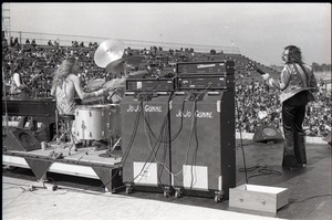 Hollywood Speedway Rock Festival: Jo Jo Gunne in performance, view from behind drummer (Curly Smith) and bassist (Jimmy Randall) looking over audience