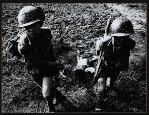 Two ARVN troops drag Viet Cong corpse